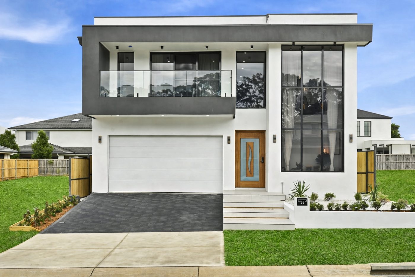 A contemporary white and charcoal double-storey home with a glass balcony and full-height corner glazing